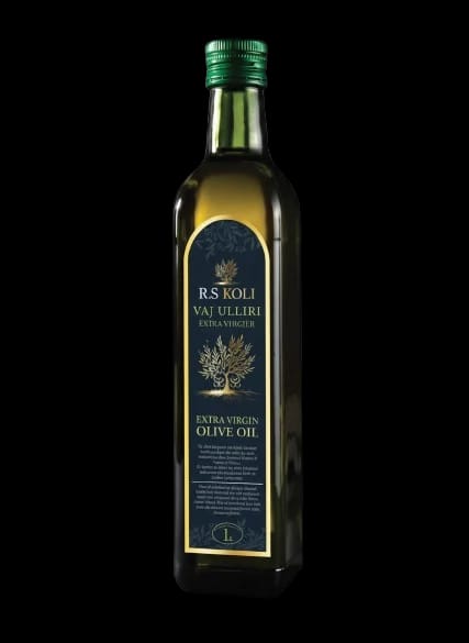 Dark glass bottle of R.S KOLI extra virgin olive oil with a sealed cap on a wooden shelf